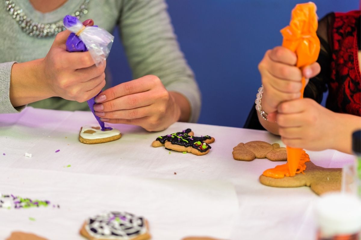 two women sitting around decorating cookies in bright colors