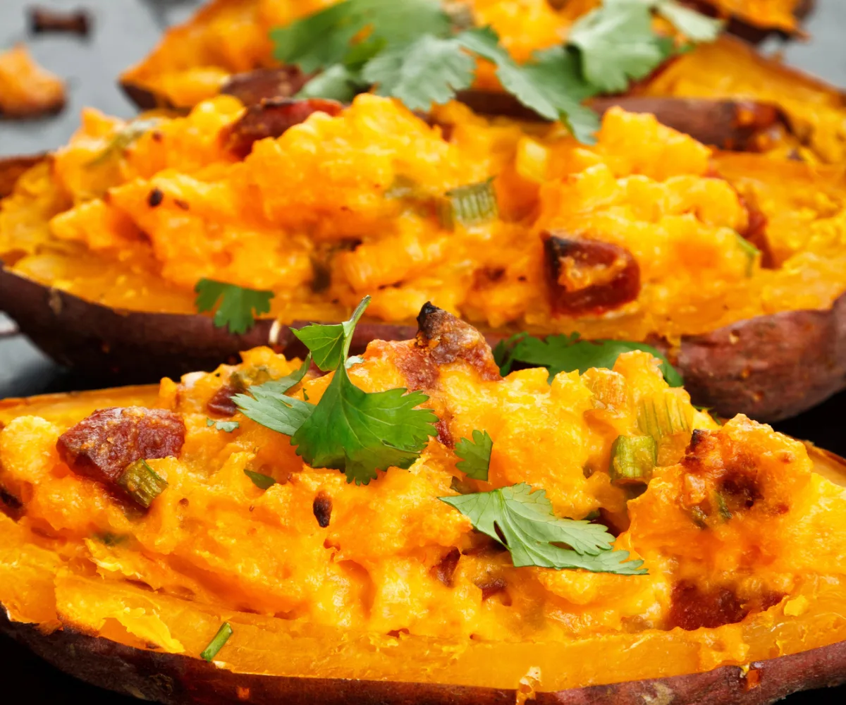 three bbq chicken stuffed sweet potatoes with parsley on top, sitting on table