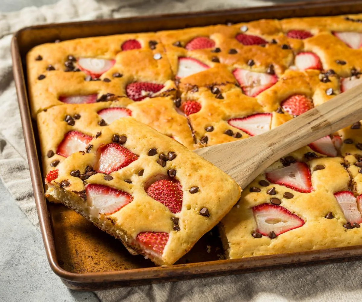 sheet pan pancakes with strawberries and chocolate chips, cut into squares to serve a crowd