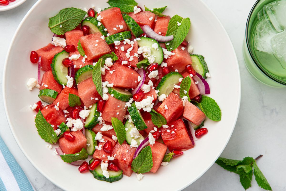 bright and fresh watermelon feta salad with green mint leaves on white table