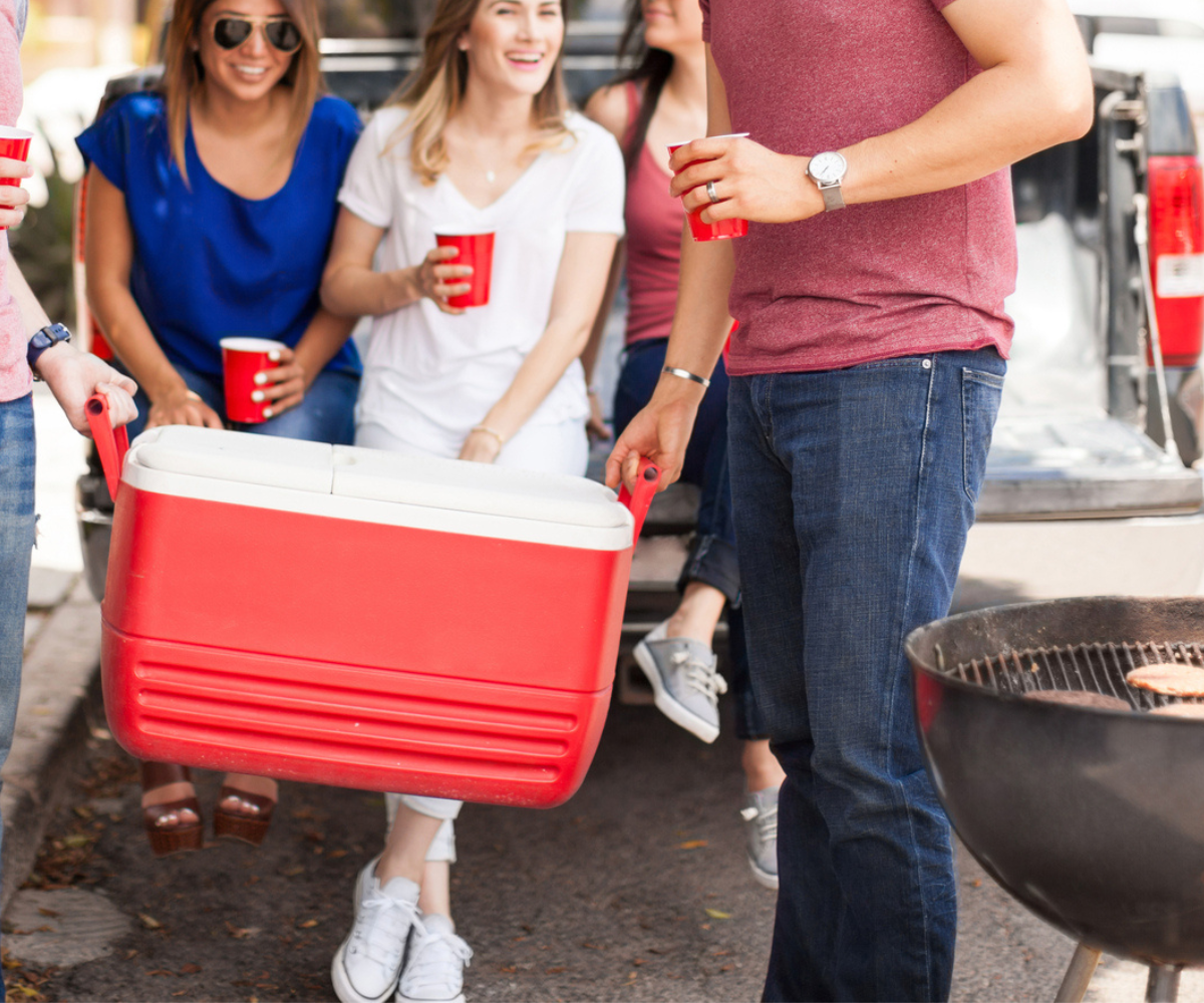 ice cooler filled with freezer meals, and adults behind it smiling and carrying it into vacation home