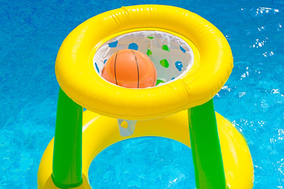 bright yellow floating basketball game in pool water on summer day