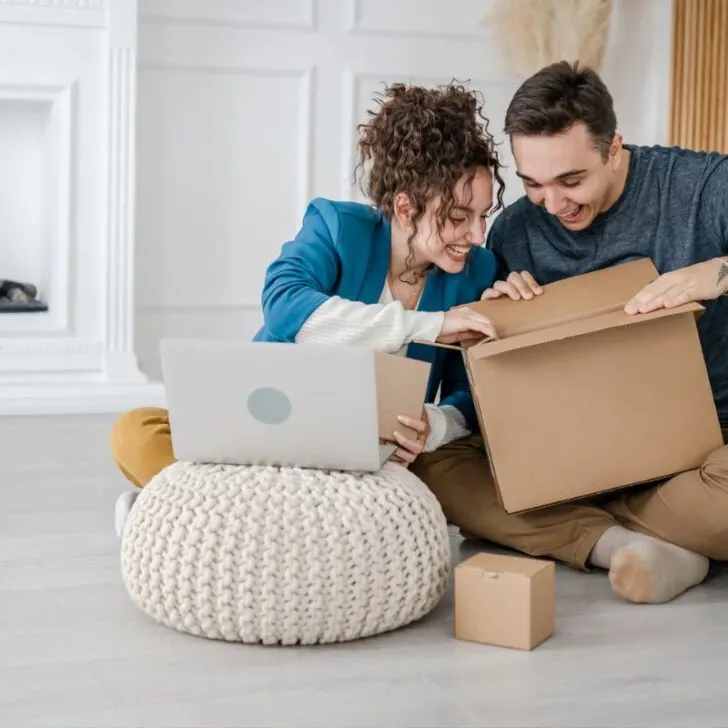 young couple excitedly opening couple's date night gift on floor