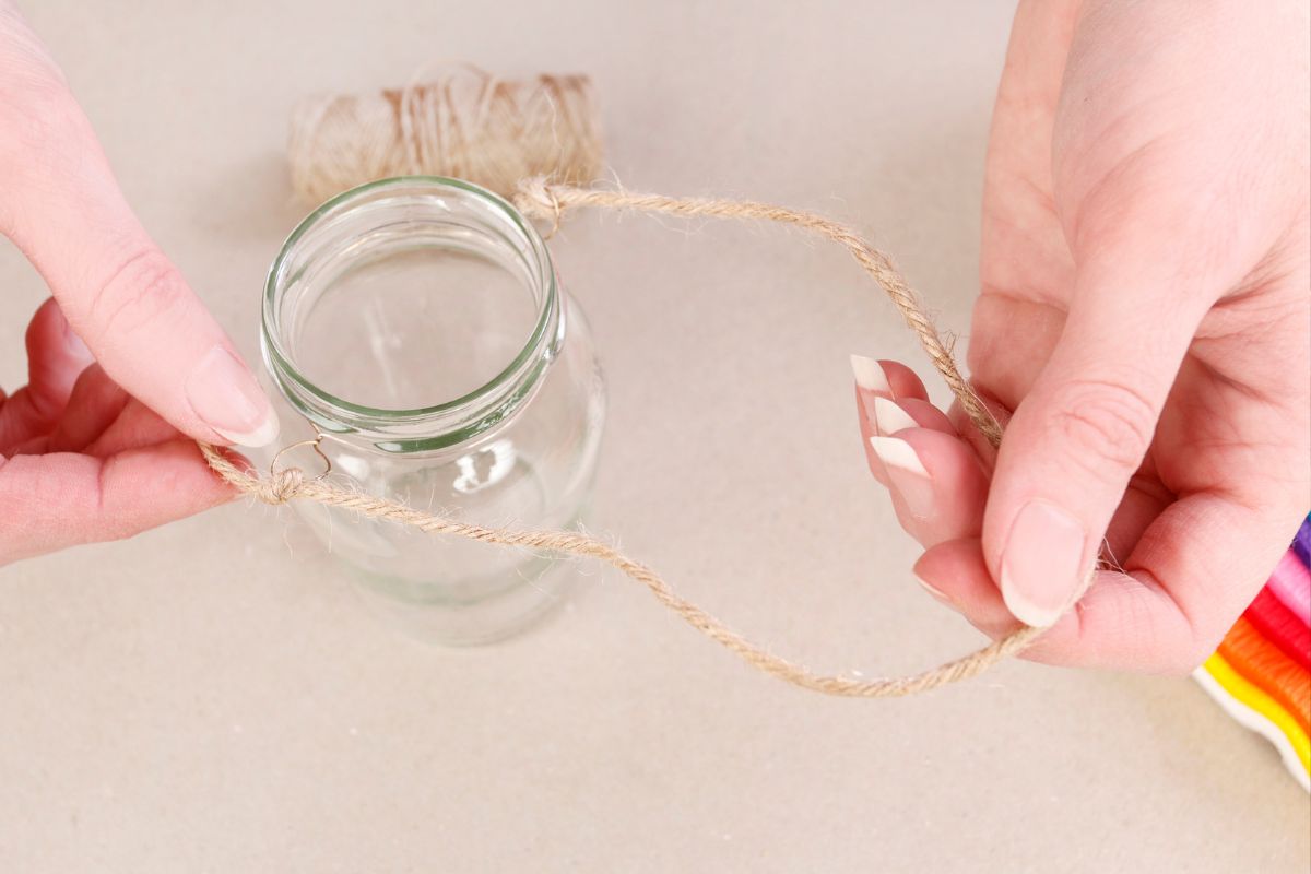 womans' manicured hands wrapping twine around mason jar DIY date night ideas gift