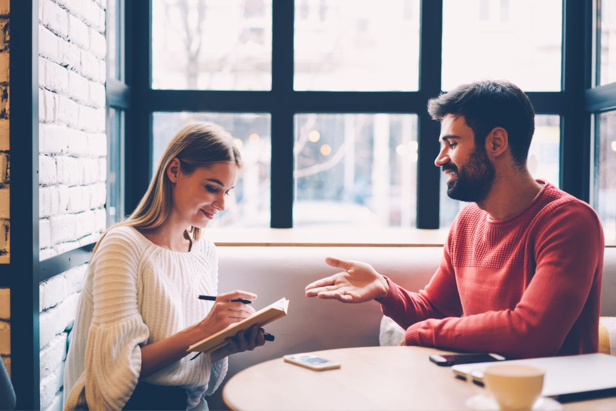 couple smiling and writing a couple's mission statement together at coffee shop