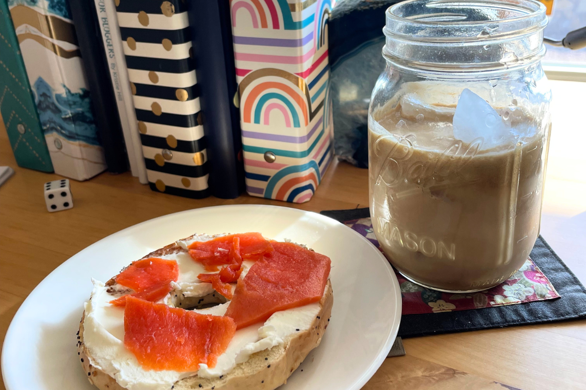 homemade iced cold brew latte with everything bagel and lox, sitting on desk with colorful binders in background