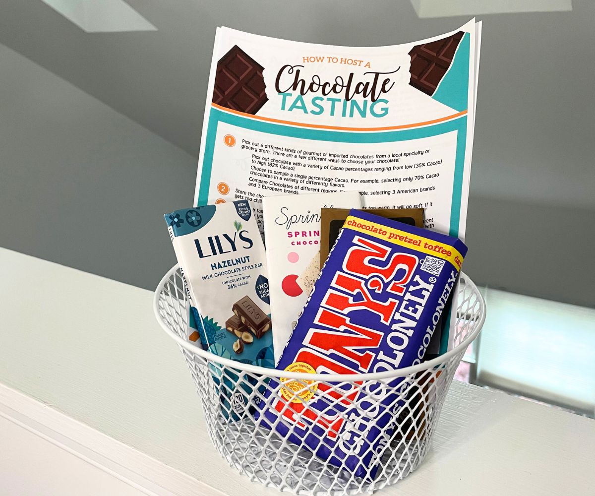 small white sire basket with printable Chocolate Tasting in back, and 5 colorful, gourmet chocolate bars