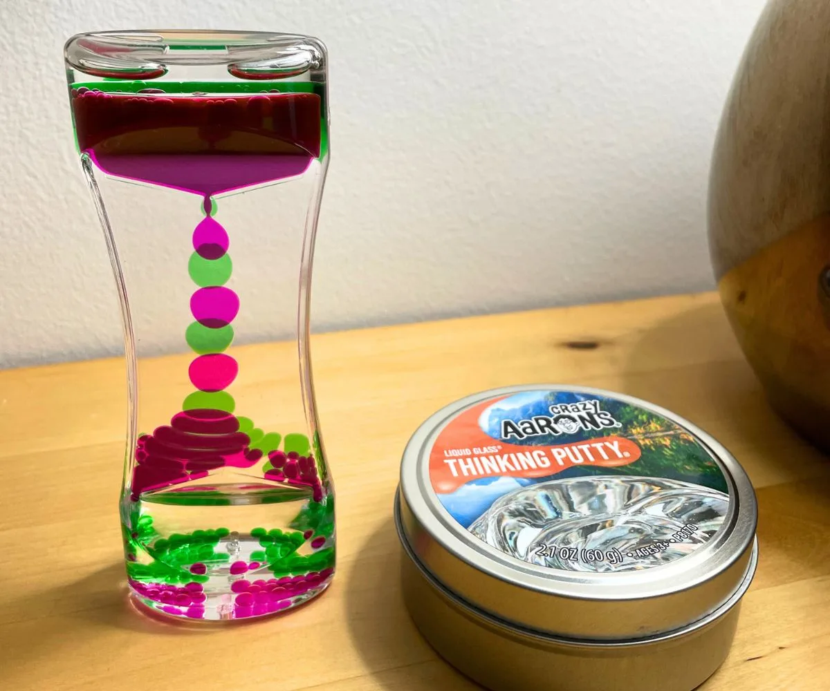 Aaron's Thinking Putty canister next to liquid motion office toy