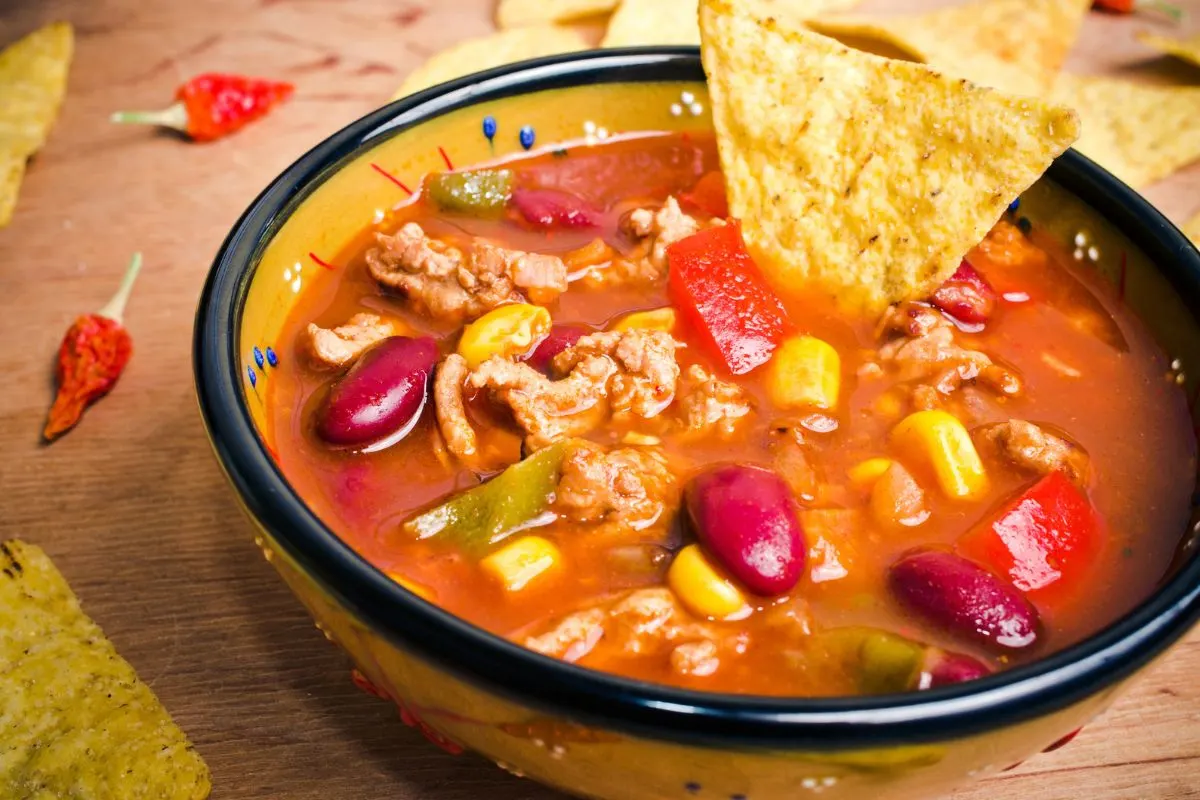 small crock bowl filled with Taco Soup, with tortilla chip coming out of it