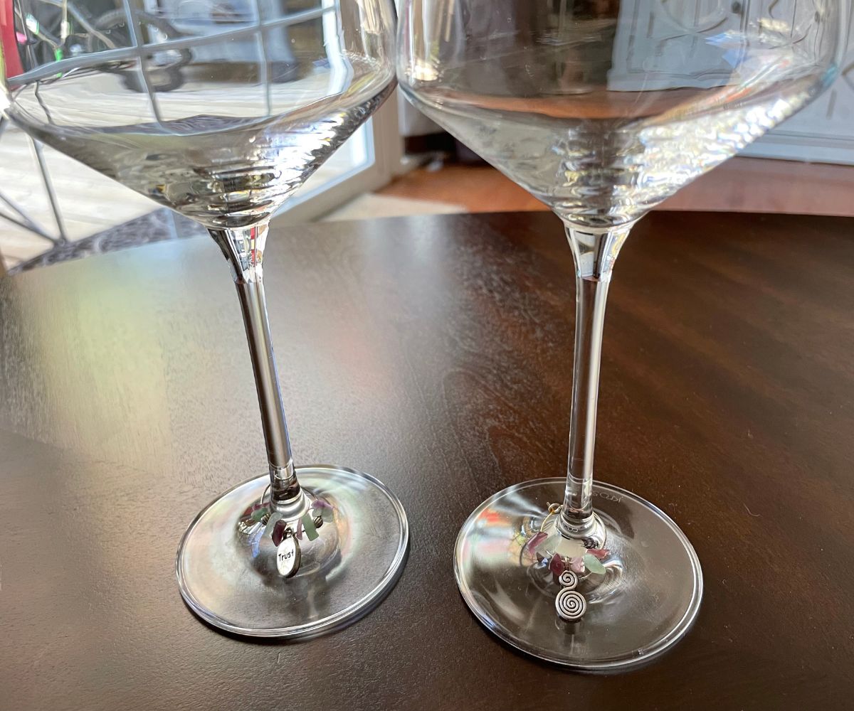 two wine glass stems on dark table, with the wine charmers