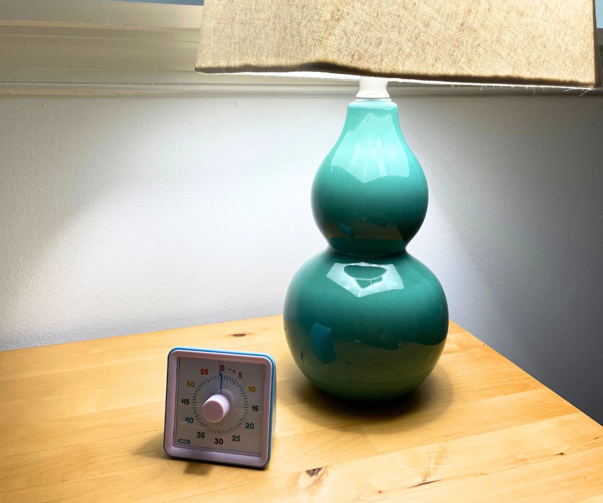 turquoise colored base lamp with square shade, on maple wood desk