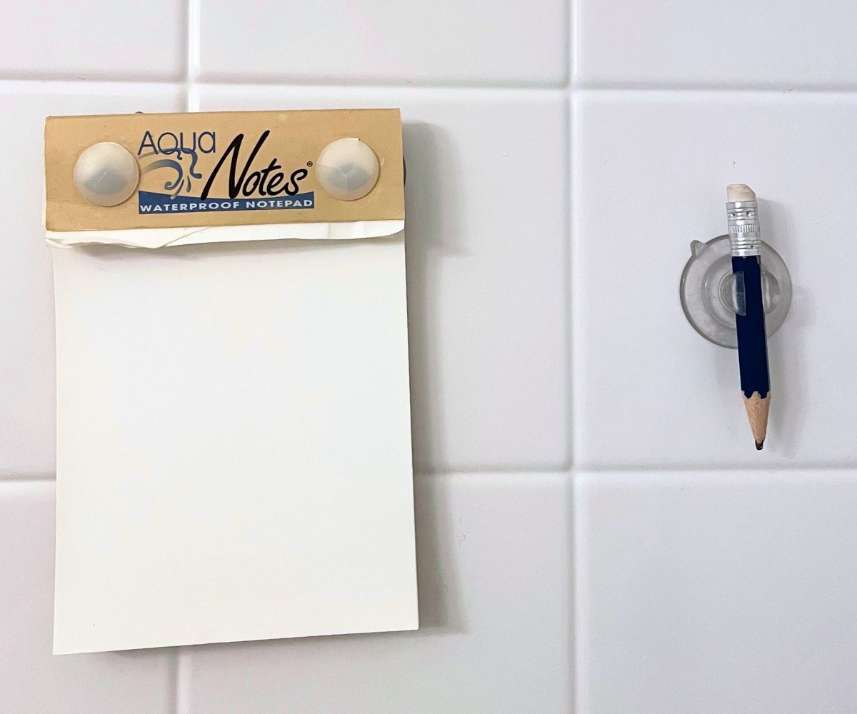 Aqua Notes waterproof notepad with pencil next to it, in a shower