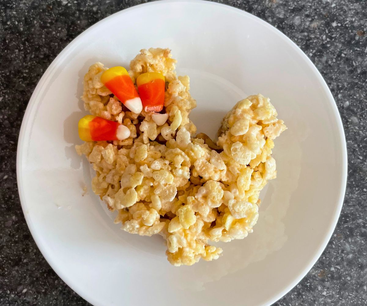 Trail mix Rice Krispies treat in shape of turkey with candy corn splayed on the tail