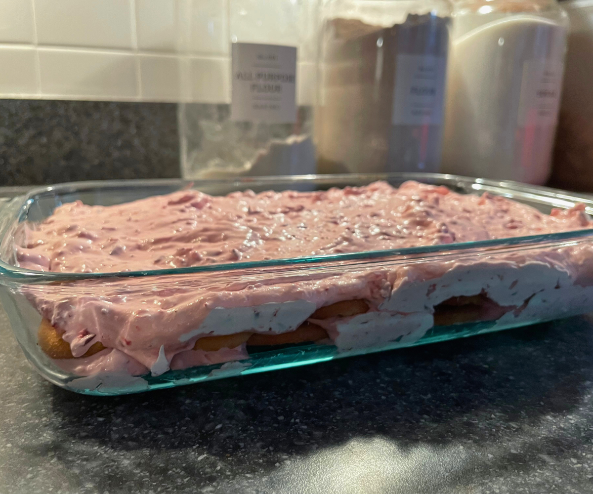 layered vanilla wafers and colorful pink cranberry heavy cream mixture in a large rectangular glass pan