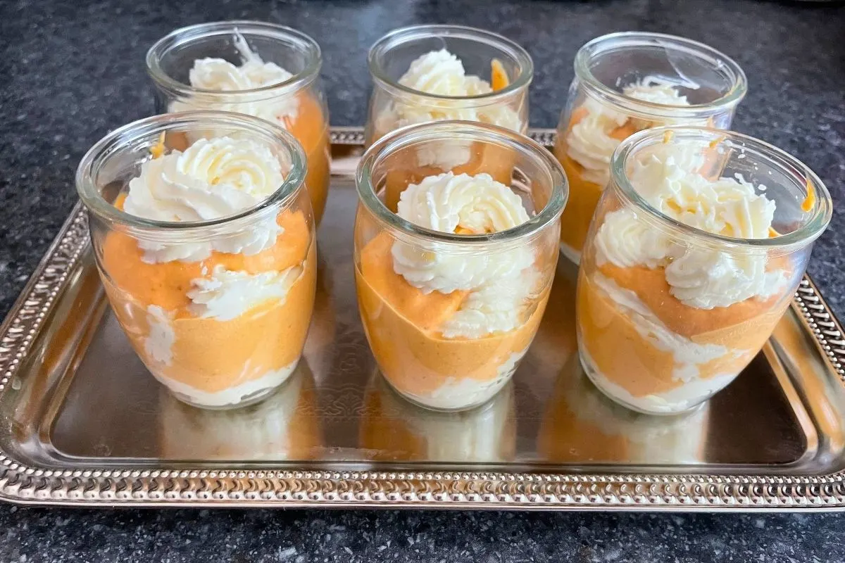 small roundish glasses of pumpkin cheesecake mousse glasses on silver tray