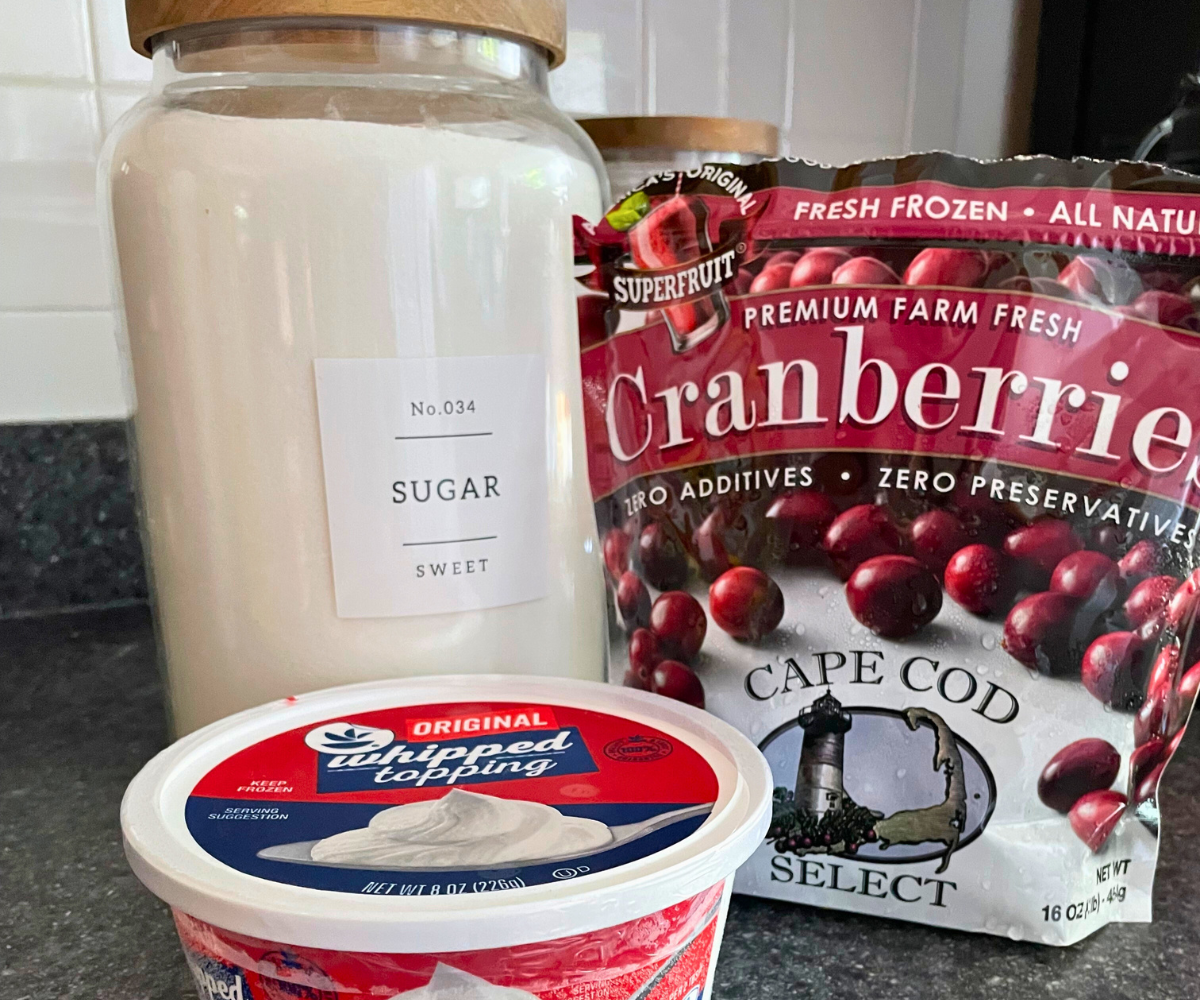 big container of sugar, bag of cranberries, and tub of whipped topping on counter