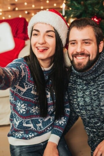 couple wearing santa hats and taking funny selfie together
