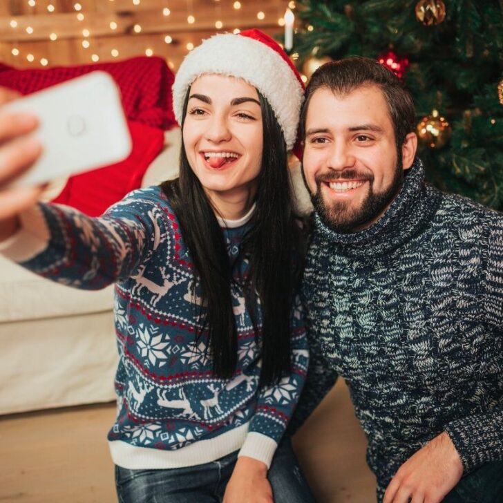 couple wearing santa hats and taking funny selfie together