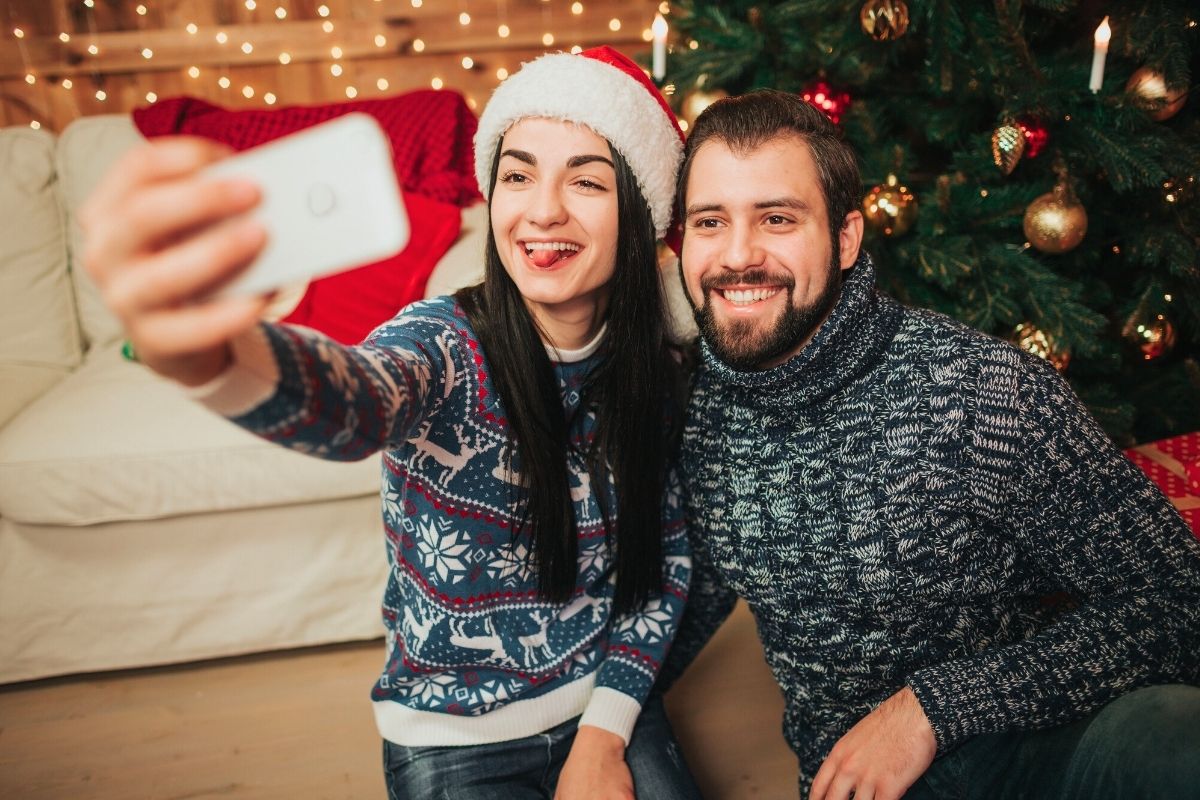 couple wearing santa hats and taking funny selfie together