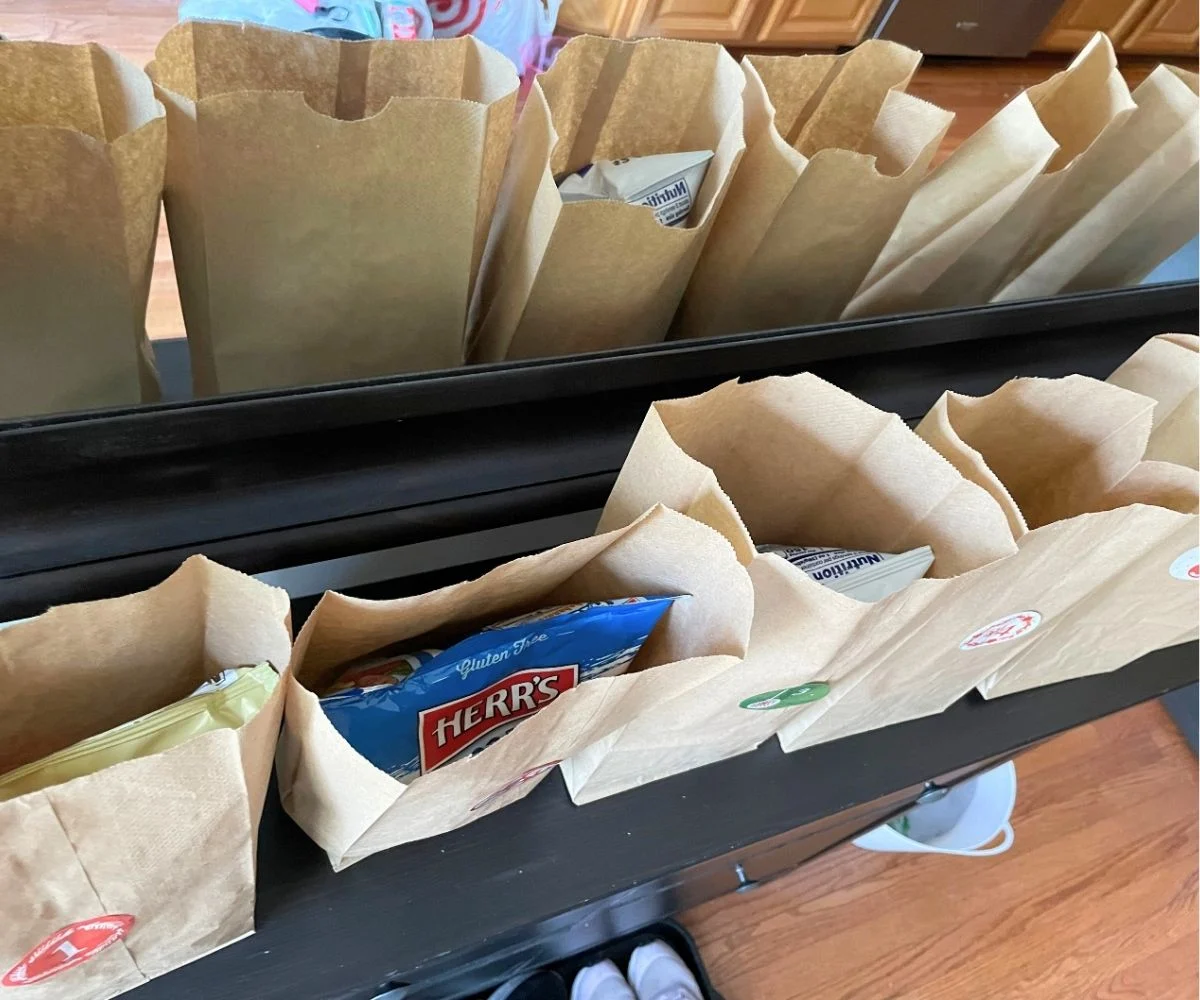 six lunch bags, each filled with different kind of Herr's potato chips