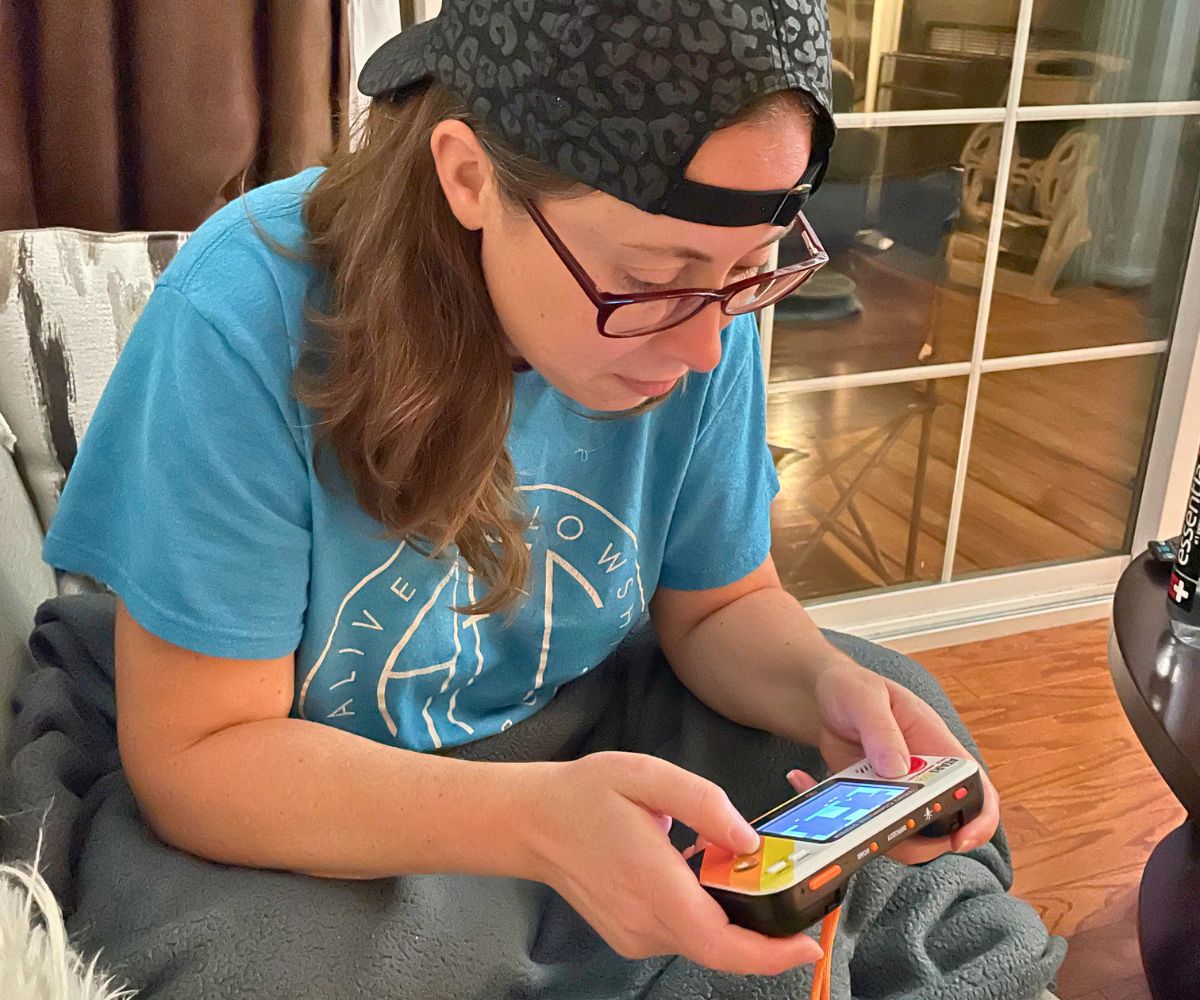 author with hat on backwards, focusing intently on retro arcade game in lap