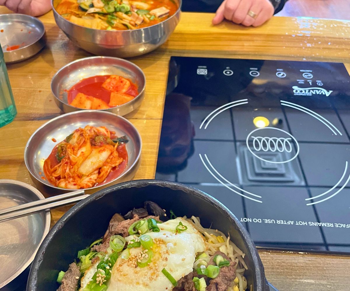 hot plate at Korean restaurant with lots of colorful foods around it