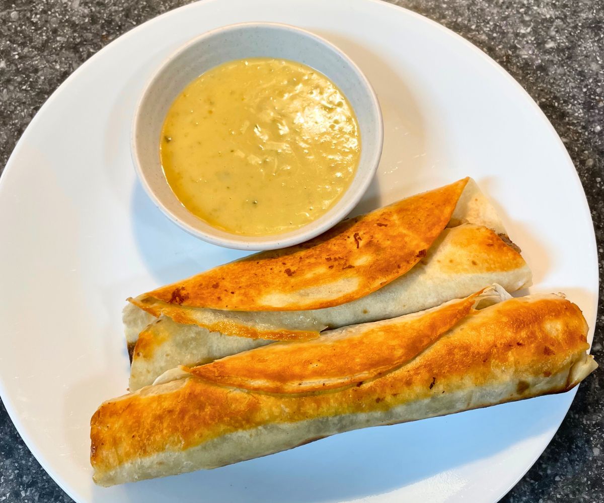 two taquitos and homemade cheese sauce