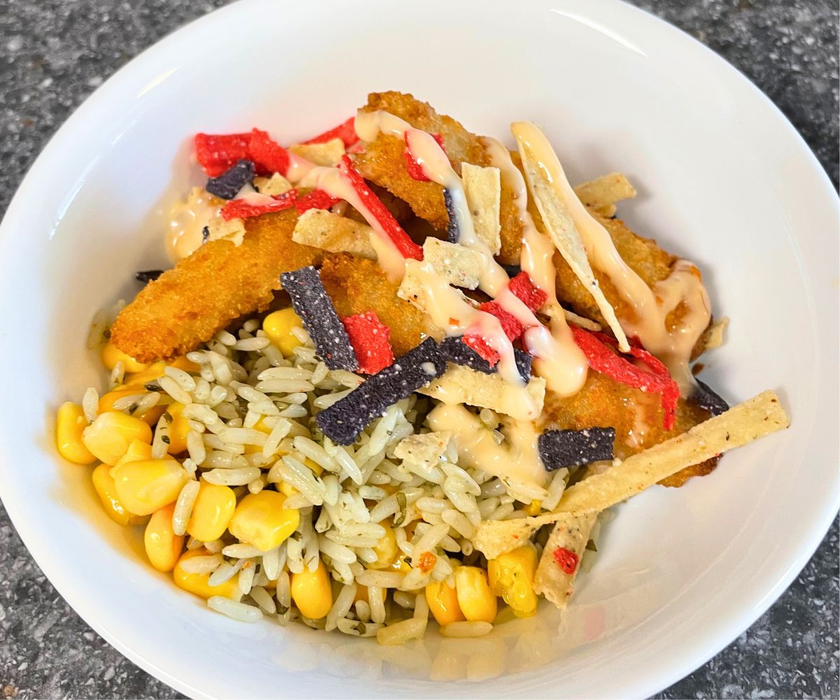 bowl with fish sticks, tortilla strips, corn, cilantro rice, sweet aioli sauce, etc.