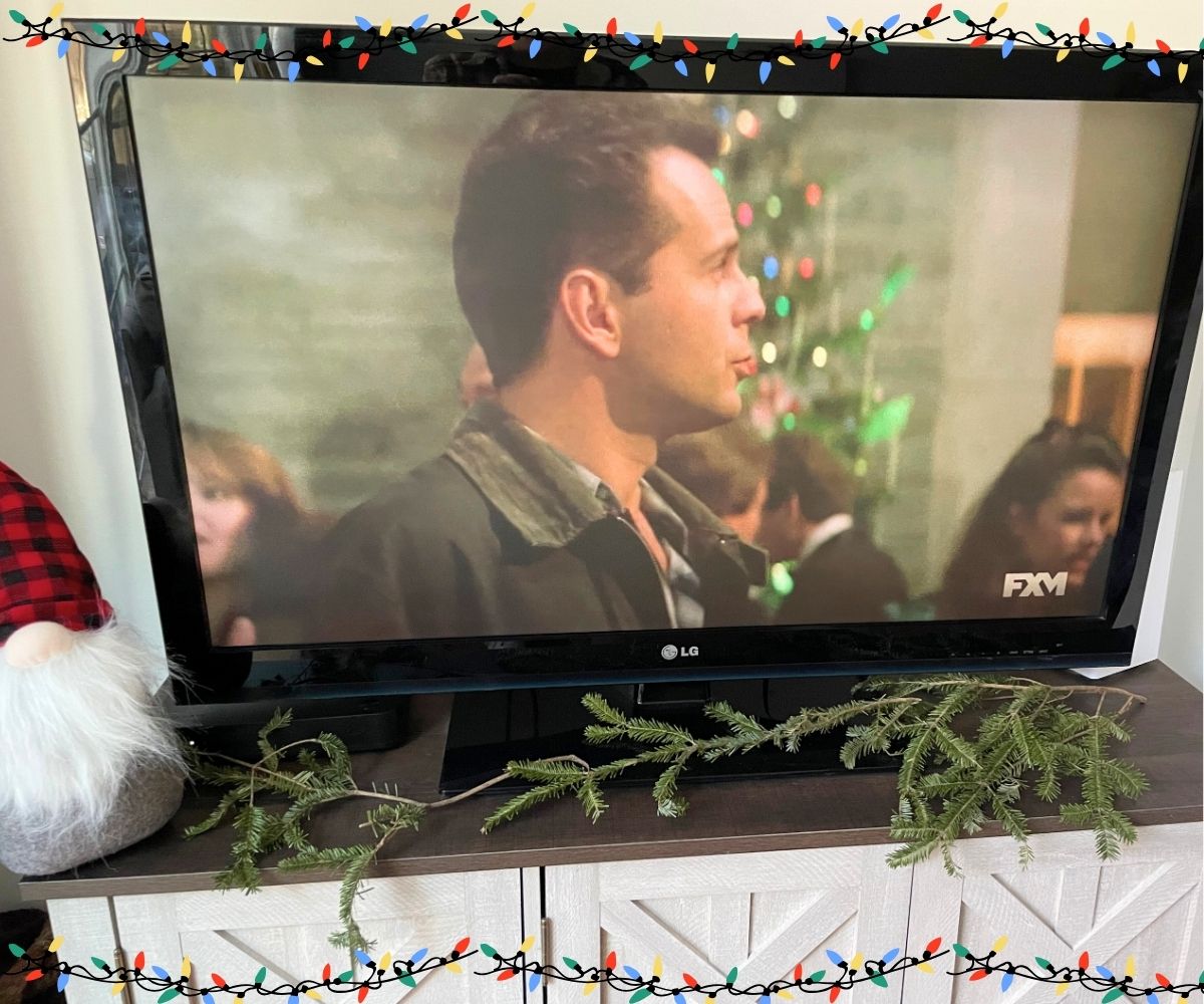John McClane at holiday party looking for wife, in front of Christmas tree, on TV