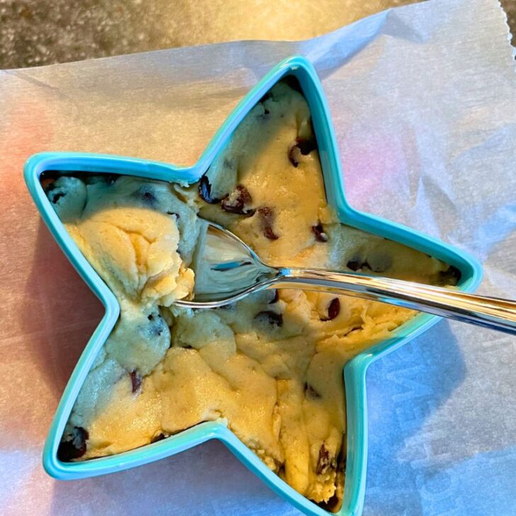 light blue star cookie cutter filled with edible cookie dough and a silver spoon