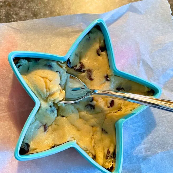 light blue star cookie cutter filled with edible cookie dough and a silver spoon