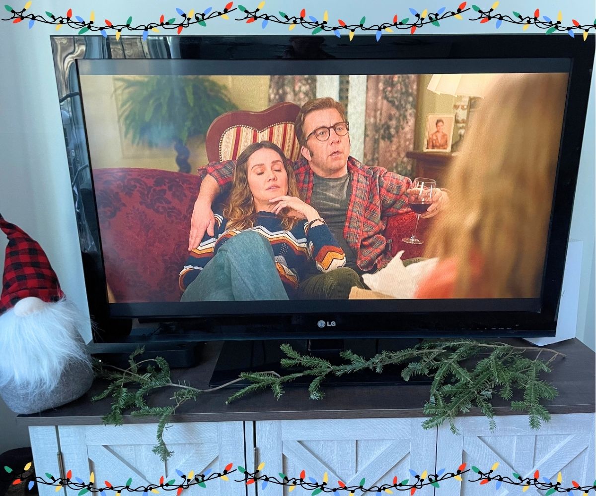 Ralphie and wife sitting on couch with wine watching kids decorate Christmas tree