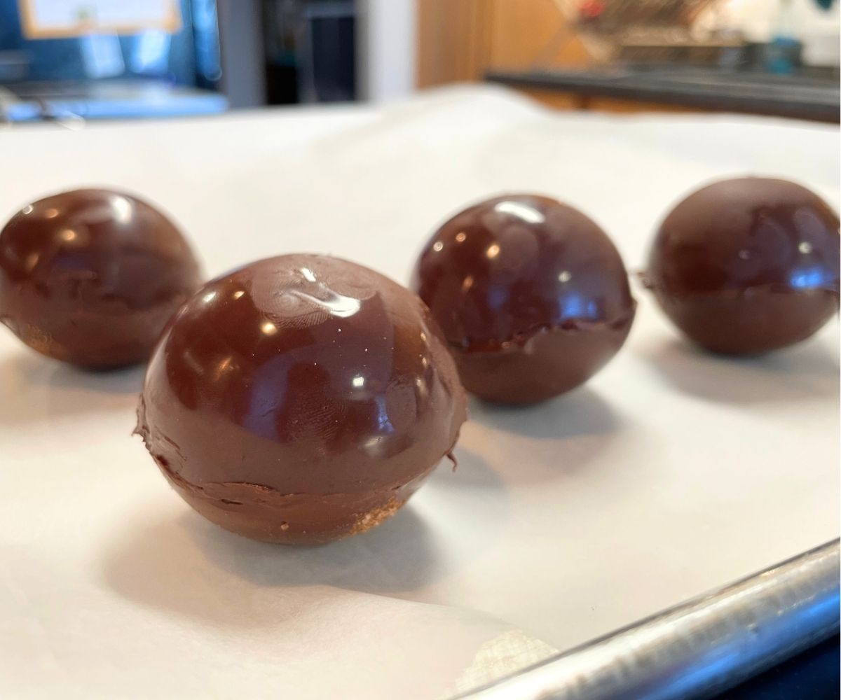 four shiny hot cocoa bombshells on parchment paper