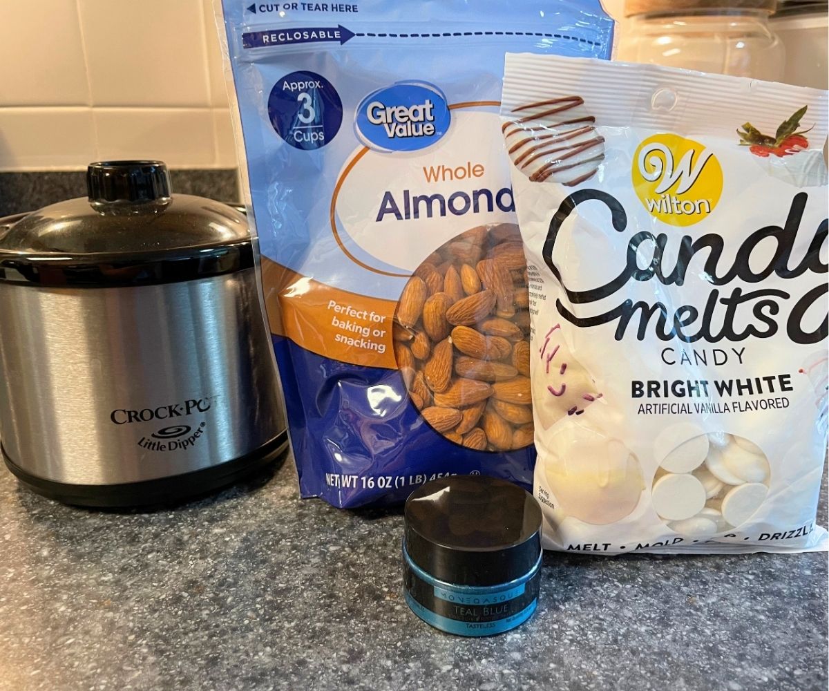 packages of candy melts, almonds, and edible glitter next to mini Crockpot on counter