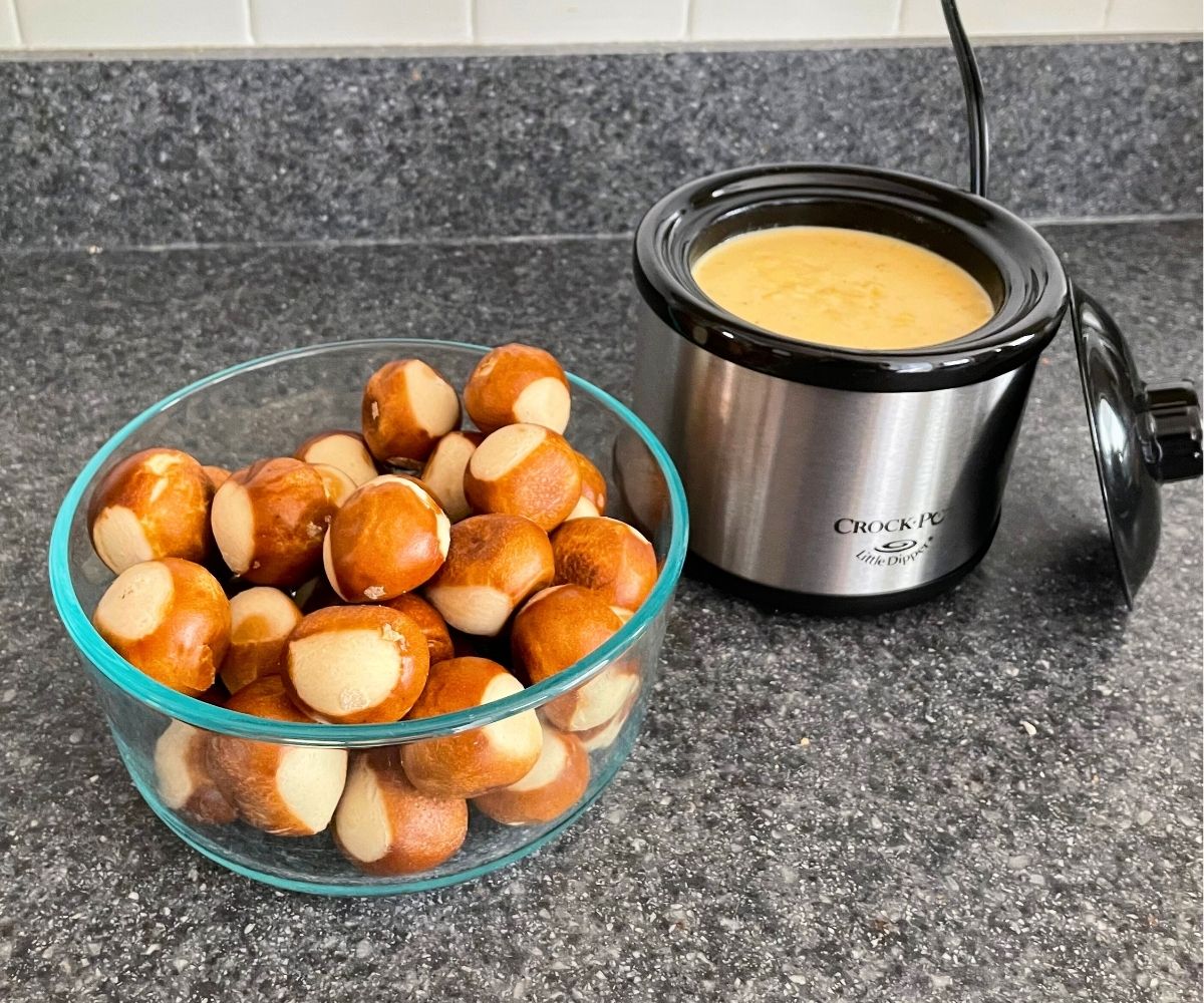 bowl of pretzel bites next to mini slow cooker filled with tex-mex cheesy sauce