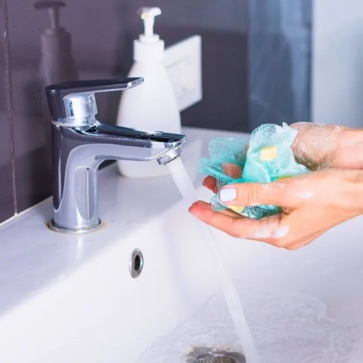 woman washing hands at sink with black wall