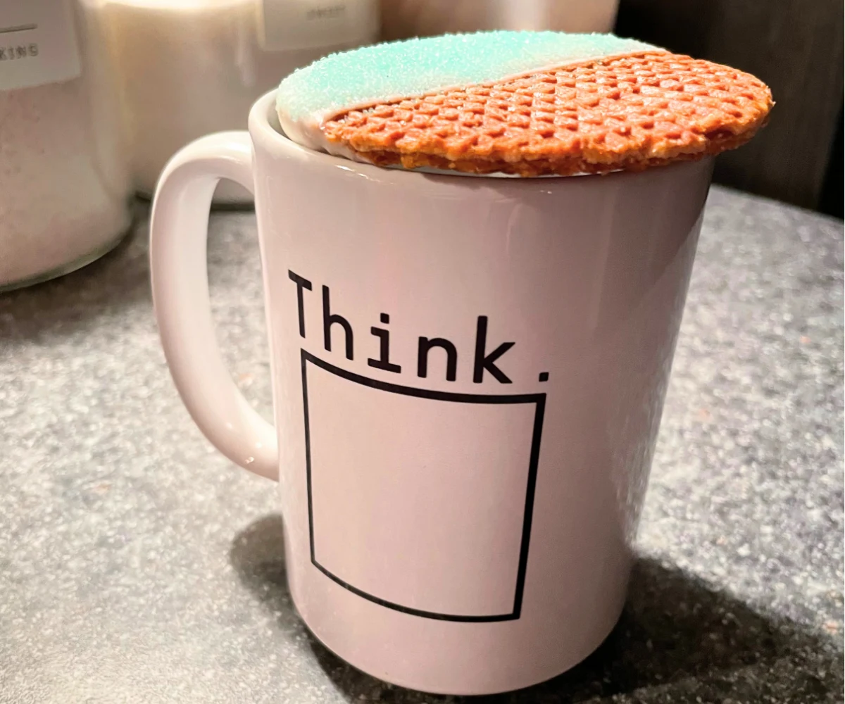 snow-dipped stroopwafel on top of white mug that has a box and says "think" on top of it