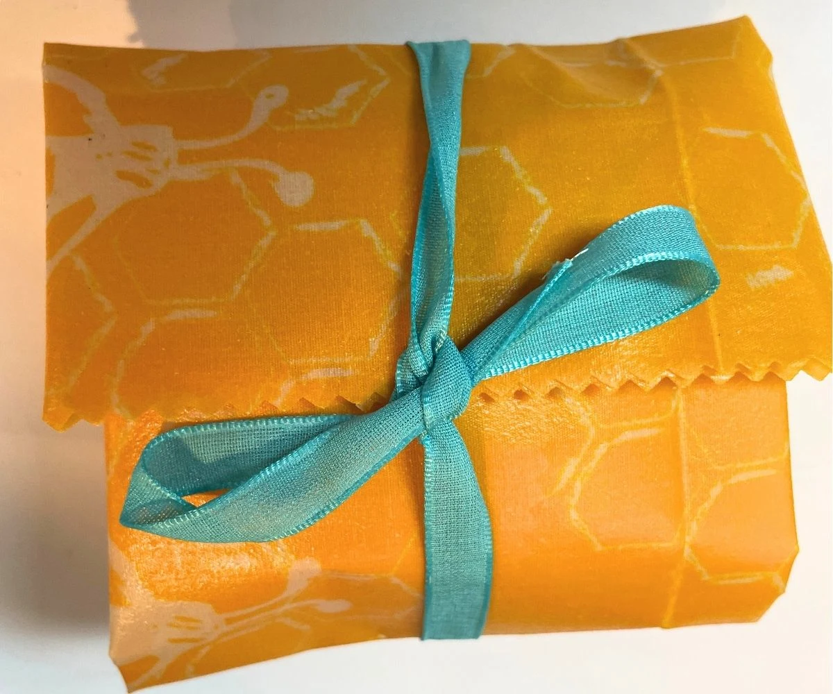 bright yellow decorated beeswax reusable food wrap tied with blue ribbon