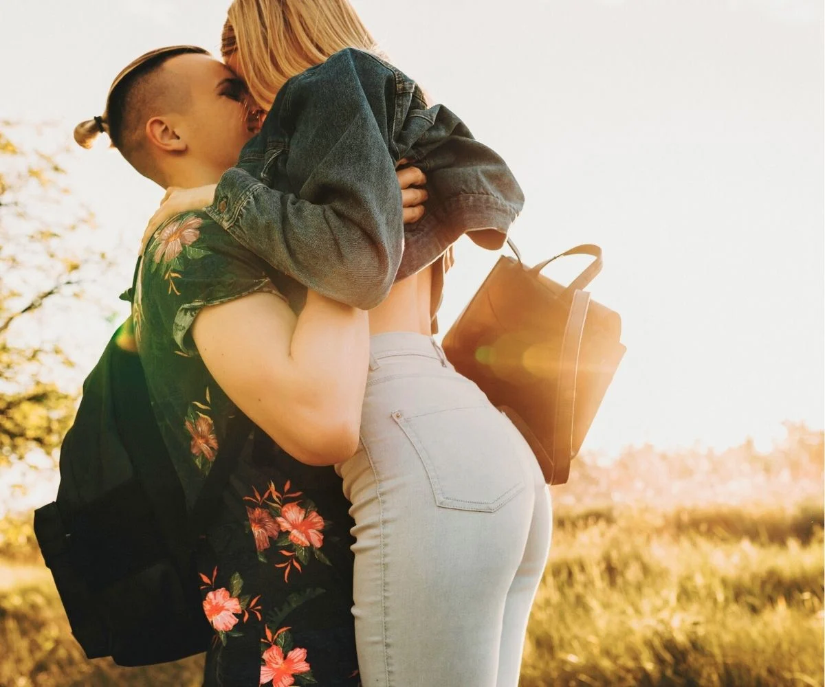 guy holding girl up out in field, taking photo