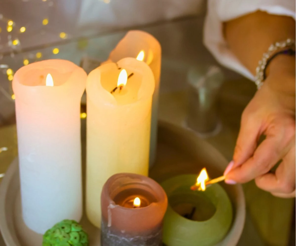 woman using match to light up mismatched candles on her table