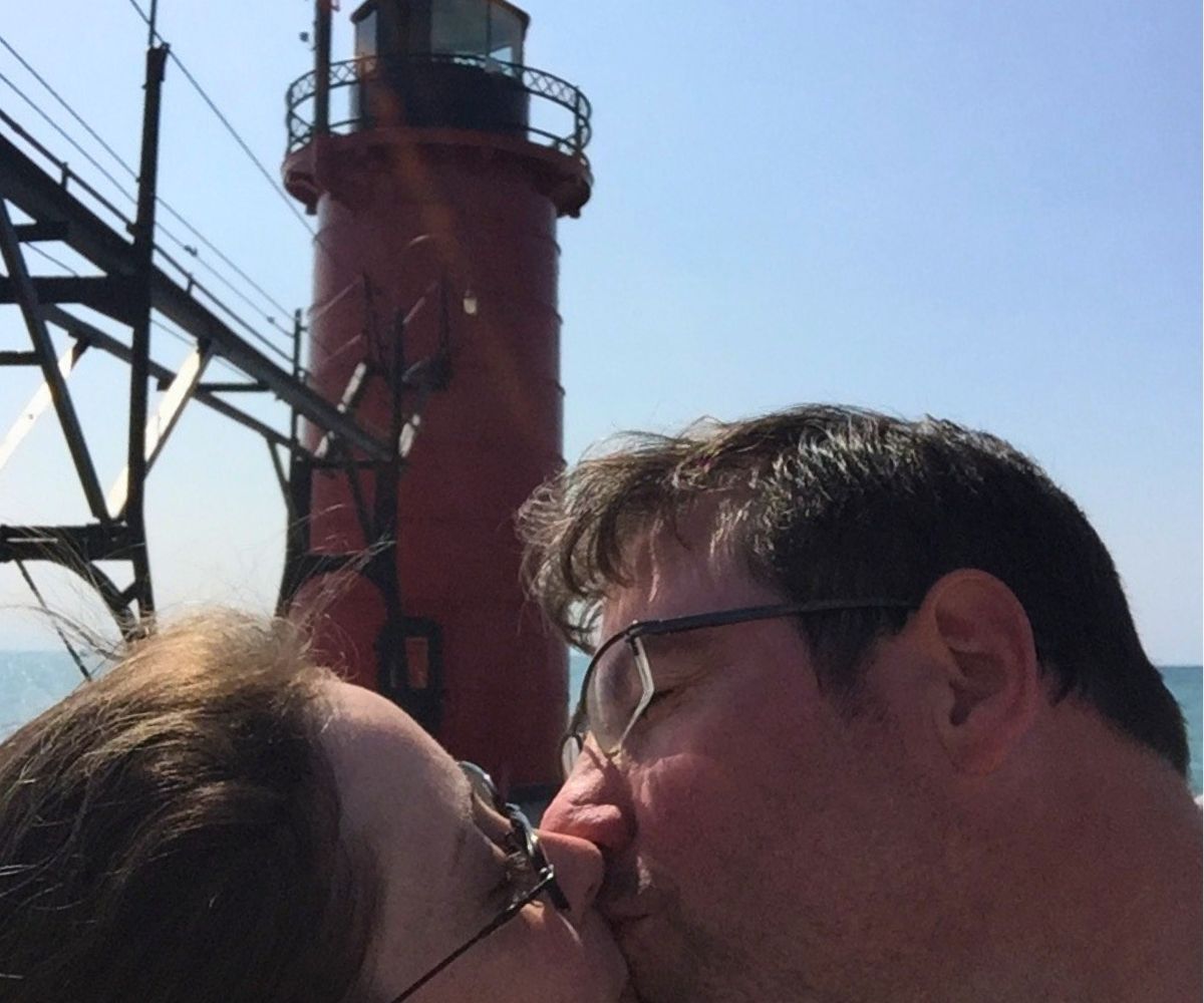 blogger and her husband smooching in front of a red lighthouse