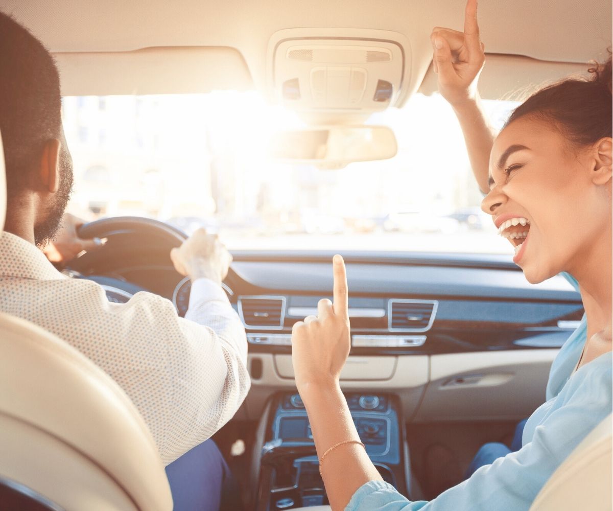man and woman having lots of fun driving in a car
