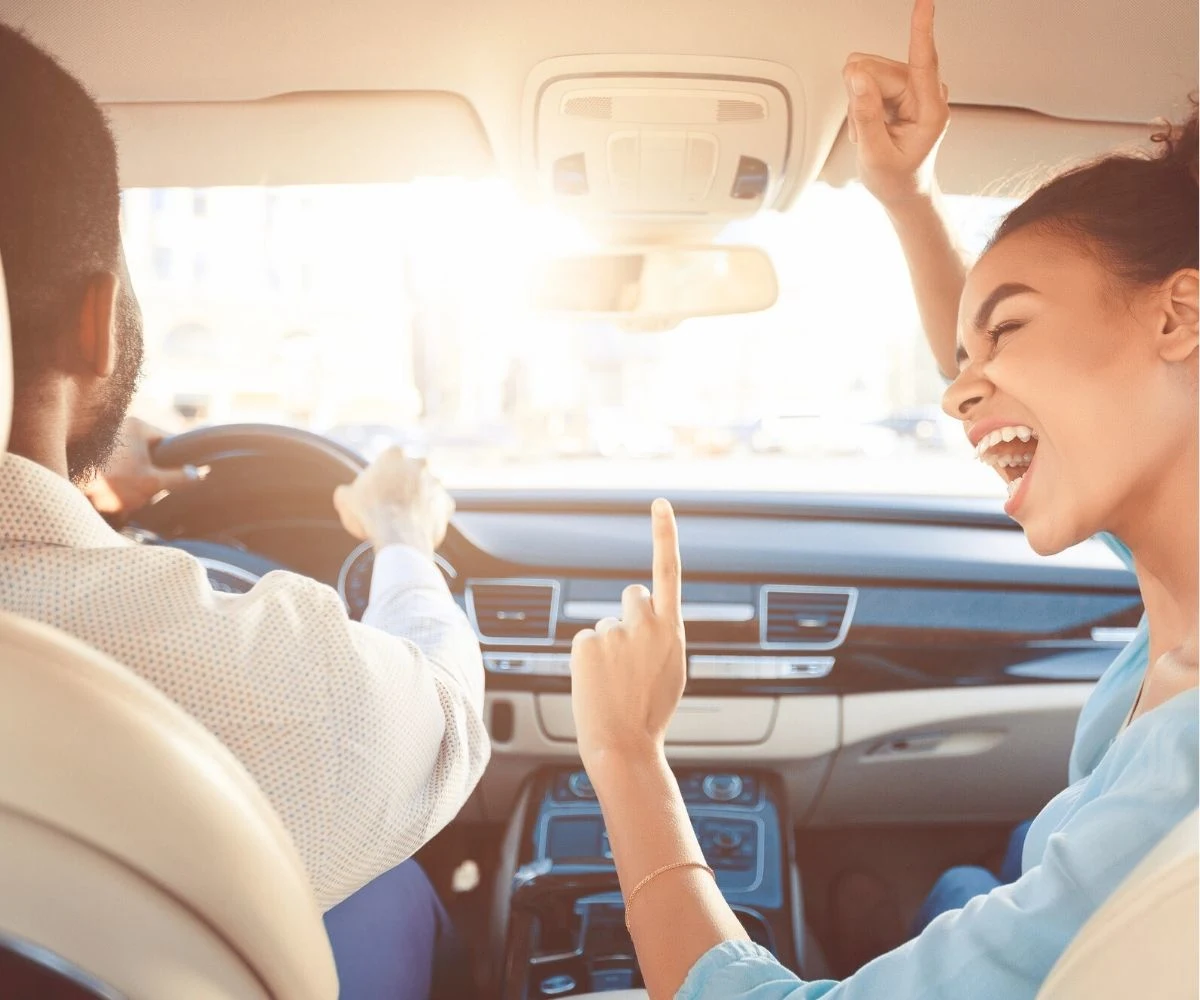 man and woman having lots of fun driving in a car