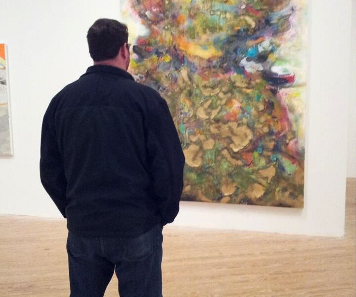 man looking at modern art piece on wall