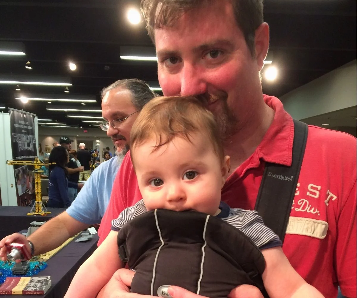husband wearing baby and smiling intently
