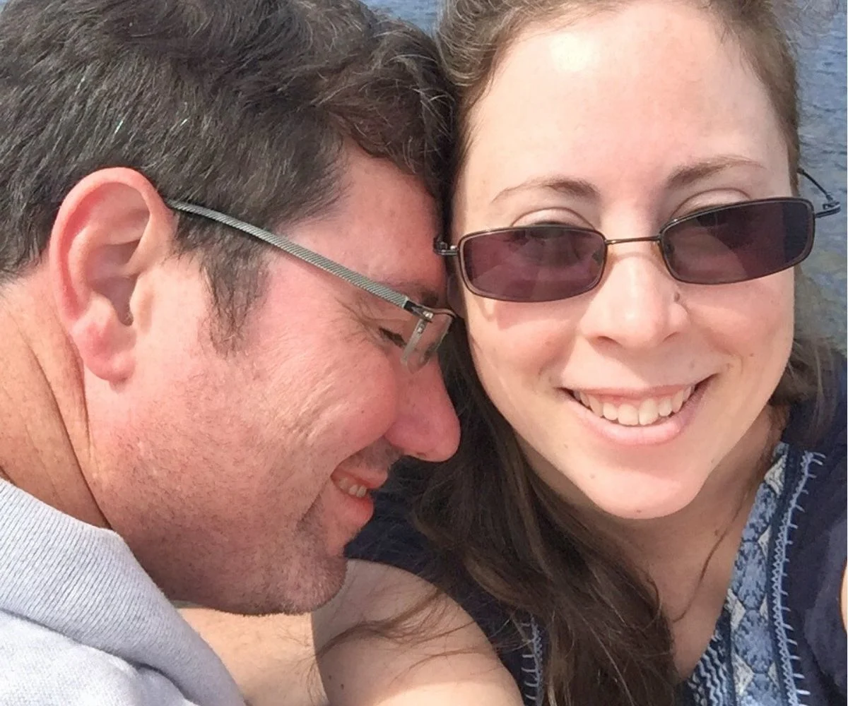 author and husband sitting on the dock, smiling