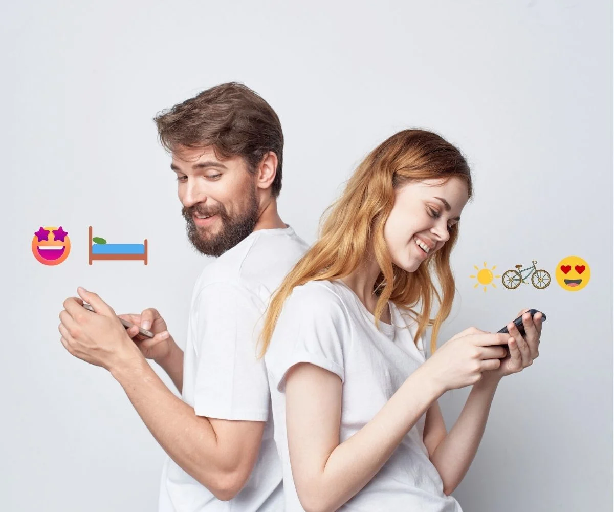 a couple with their backs to each other with phones, and emojis on either side of them
