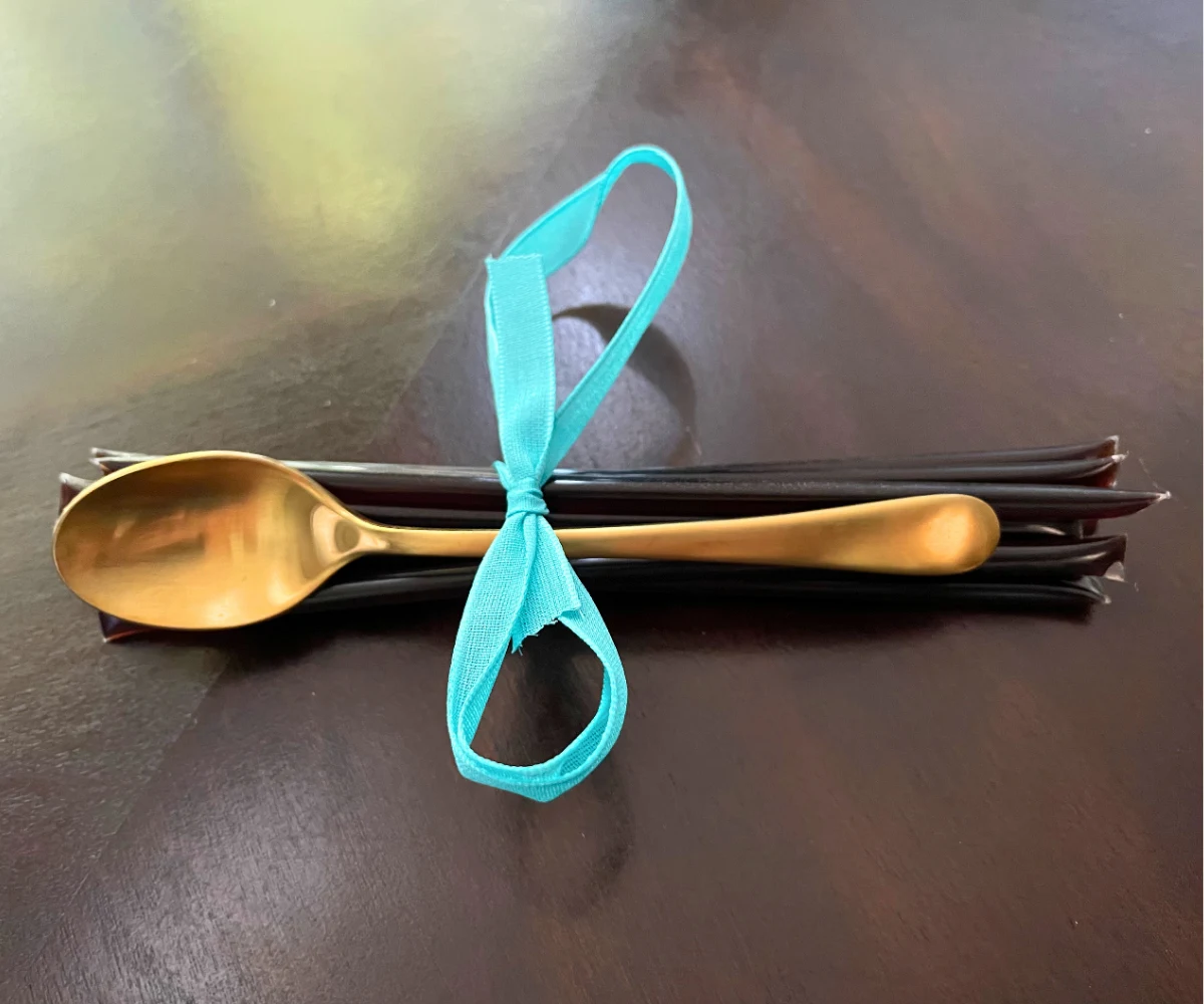 cluster of honey elderberry sticks and a golden mini spoon tied together in a bright blue bow