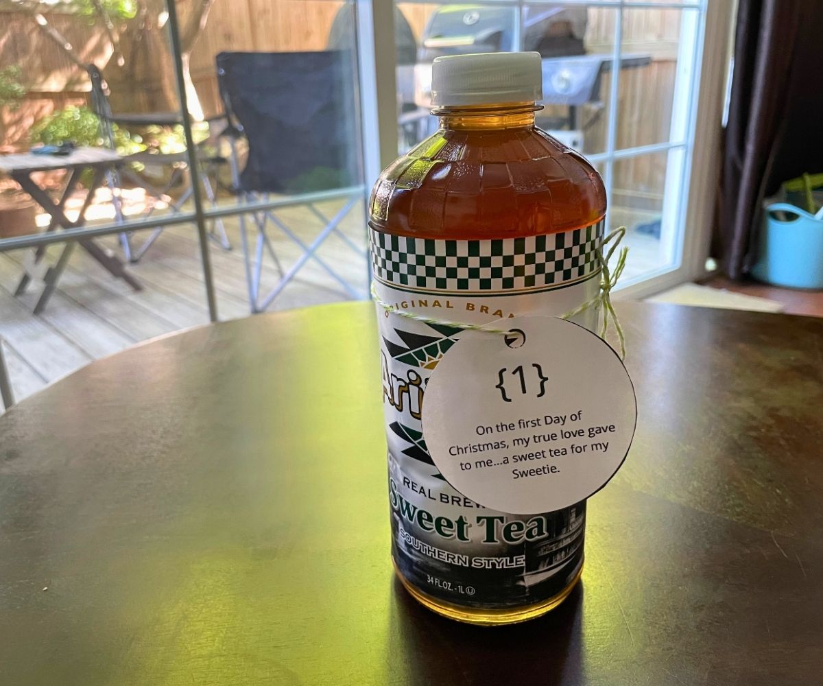 large bottle of Sweet Tea with ornament tag tied to it on dark table