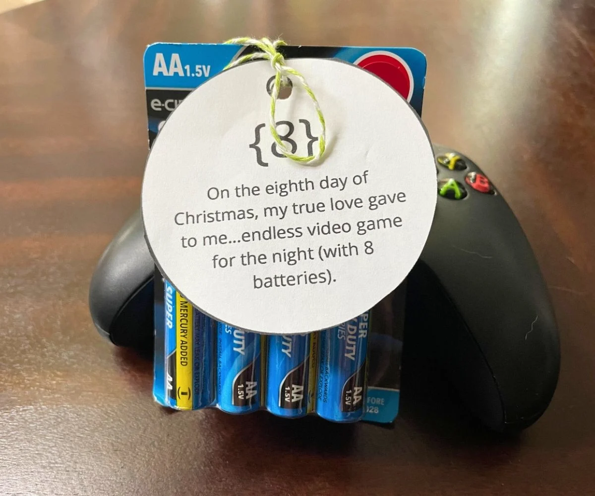 8-pack of batteries sitting on top of Xbox remote, wrapped in ornament-shaped tag